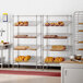 A rack of Regency chrome slanted wire shelves holding baked goods in a bakery.