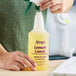 A person pouring Noble Chemical Lemon Lance disinfectant into a labeled bottle.