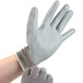 A person wearing a pair of Cordova medium grey gloves with a gray polyurethane palm coating.