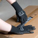A person wearing Cordova black polyester gloves with black polyurethane palm coating.