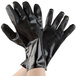 A pair of hands wearing black rubber gloves with a white background.