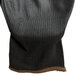A black cloth glove with black polyurethane on the palm and brown edge.