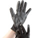 A pair of black Cordova polyester gloves with black polyurethane palms.