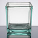 A clear square glass container with a Cal-Mil clear glass jar lid on a table.