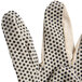 A close up of a Cordova medium weight canvas glove with black dots on the palm.