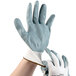 A pair of hands wearing Cordova white nylon gloves with gray foam nitrile palms.