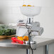 A Weston Roma Food Strainer and Sauce Maker juicer on a counter with oranges and a bag of vegetables.