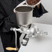 A person pouring coffee beans into a Weston Corn and Grain Grinder.