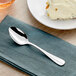 An Acopa Benson stainless steel spoon on a napkin next to a plate of ice cream.
