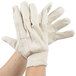 A pair of hands wearing Cordova standard weight white cotton canvas work gloves.
