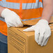 A person wearing Cordova Standard Weight Cotton Canvas work gloves opening a box.