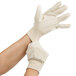 A person wearing white Cordova canvas work gloves.