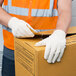 A man wearing Cordova medium weight canvas work gloves and a safety vest holding a box.