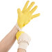 A person holding two yellow Cordova Ruffian warehouse gloves in one hand.