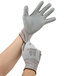 A pair of hands putting on extra-large Cordova gray polyurethane coated gloves.