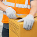 A person wearing Cordova gray jersey work gloves and a hard hat is packing a box.