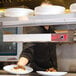 A man using an Avantco high wattage strip warmer to prepare food on a counter.