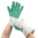 A pair of hands wearing green and white Cordova warehouse gloves.