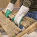 A person wearing Cordova green double palm work gloves holding pallets.