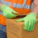 A person wearing Cordova Hi-Vis lime work gloves and holding a box.