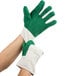 A pair of hands wearing green and white Cordova heavy weight work gloves.