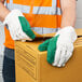 A man wearing Cordova green cotton work gloves and a safety vest holding a box.