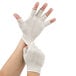 A pair of hands putting on Cordova natural polyester and cotton fingerless gloves.