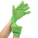 A person's hand wearing Cordova Hi-Vis lime green work gloves.