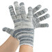 A pair of hands wearing Cordova jersey work gloves with grey and white stripes.