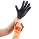 A person wearing Cordova Hi-Vis orange and black gloves.