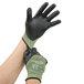 A pair of hands putting on black and green Cordova Power-Cor cut resistant gloves.