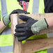 A pair of hands wearing Cordova Power-Cor cut resistant gloves holding a piece of wood.