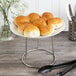 A Choice chrome plated steel display stand holding a plate of bread on a table.
