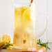 A glass pitcher of Narvon lemonade with ice and lemons.