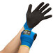 A pair of extra large blue gloves with black palm coating on a person's hands.