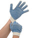 A pair of hands wearing Cordova medium weight work gloves with blue PVC coating on the palms.
