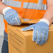 A person wearing Cordova medium weight work gloves with blue palm coating holding a box.