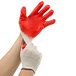 A person putting on a pair of large red and white Cordova work gloves.