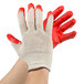 A pair of hands wearing Cordova work gloves with red latex palms, covered in red paint.