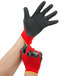 A person putting on a pair of Cordova red and black warehouse gloves.