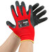 A pair of hands wearing red and black Cordova warehouse gloves with dark gray latex palms.