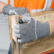 A person wearing Cordova Monarch cut resistant gloves with nitrile dots holding a piece of wood.