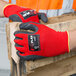 A person wearing Cordova red nylon gloves with dark gray latex palm coating.