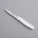 A Choice 4" Serrated Edge Paring Knife with a white handle on a gray surface.