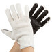 A pair of hands wearing Cordova work gloves with black PVC palm coating over white fabric.