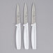 Three white Choice paring knives with white handles.