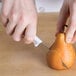 A person using a Choice paring knife to cut a pear.