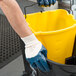 A person wearing a Cordova blue nitrile glove holding a yellow bucket.