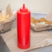 A red Choice squeeze bottle of ketchup on a table with fries.