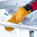 A person wearing Cordova Freeze Beater leather mittens holding a metal bar with snow on it.